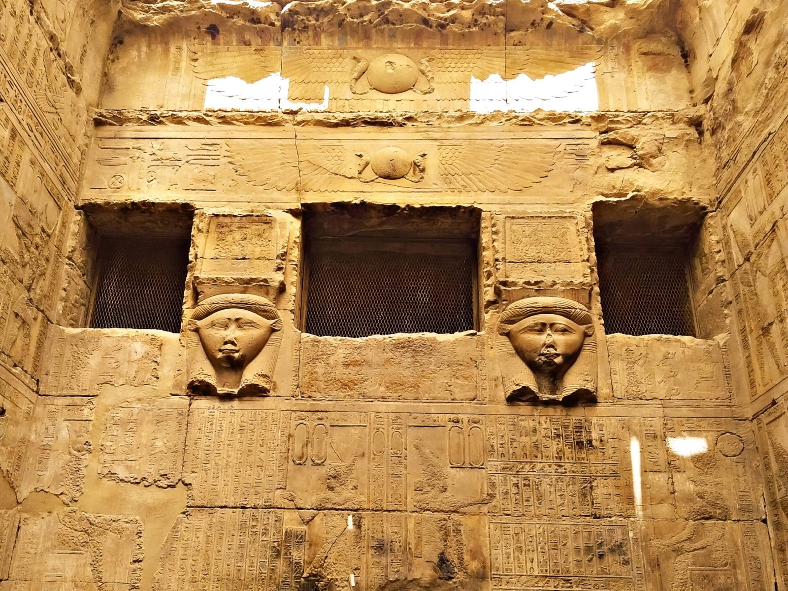 Due volti di Hathor scolpiti ai lati di una finestra in una cappella del tempio di Dendera
