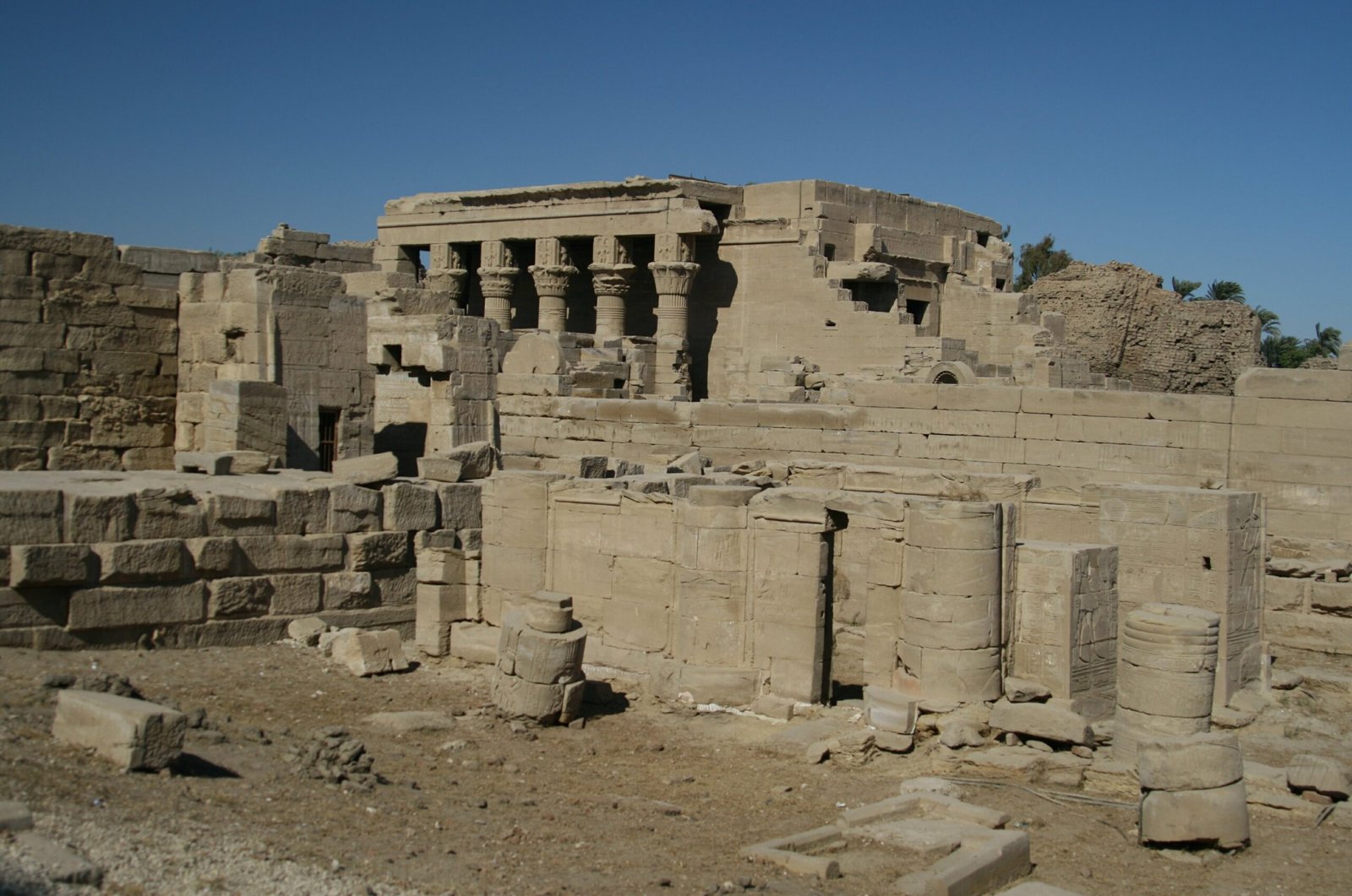 Le colonne del tempio della nascita di Dendera tra le rovine del recinto, sotto un cielo azzurro