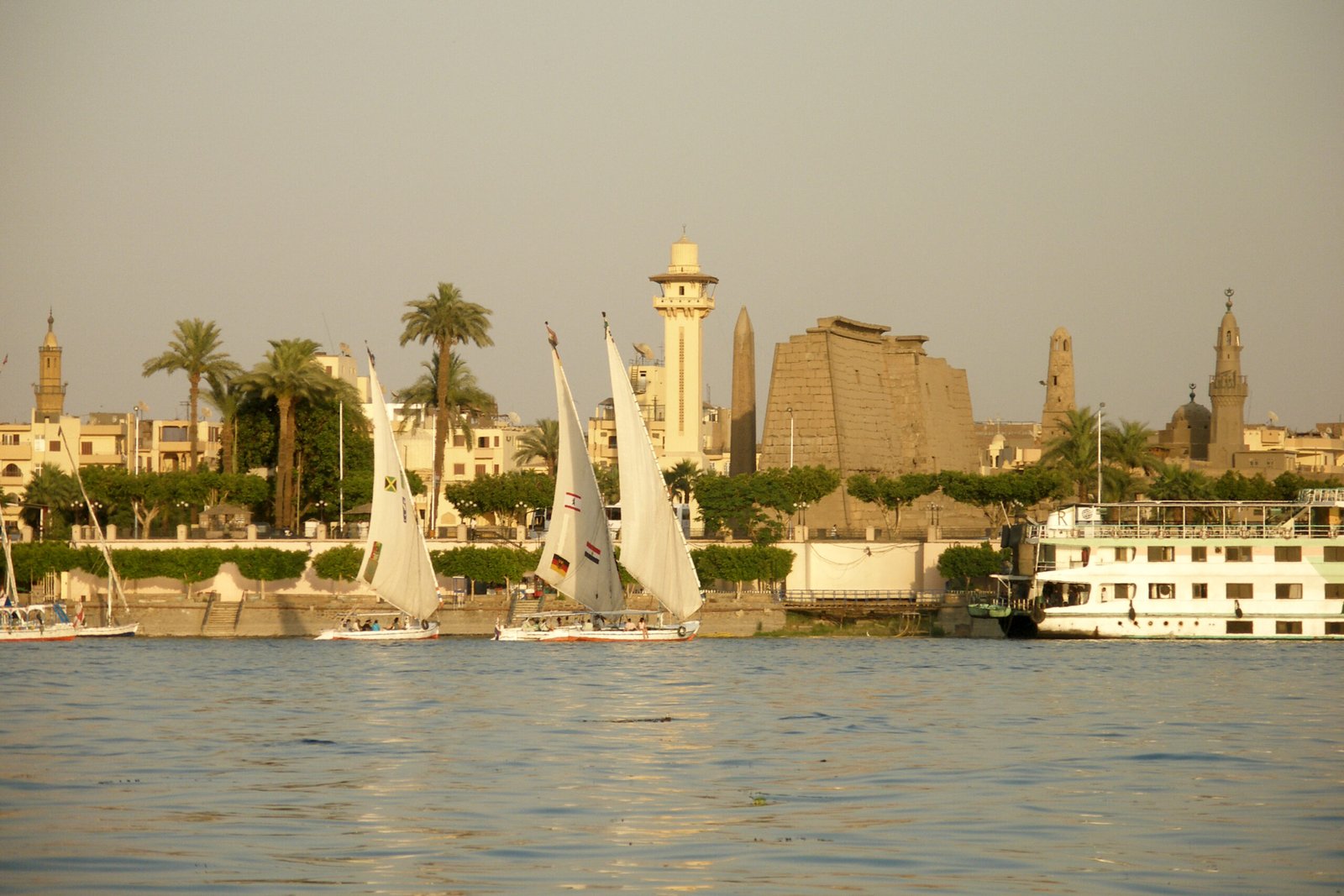 Il lungofiume di Luxor con le feluche, il pilone del tempio e il minareto illuminati dal sole del tardo pomeriggio