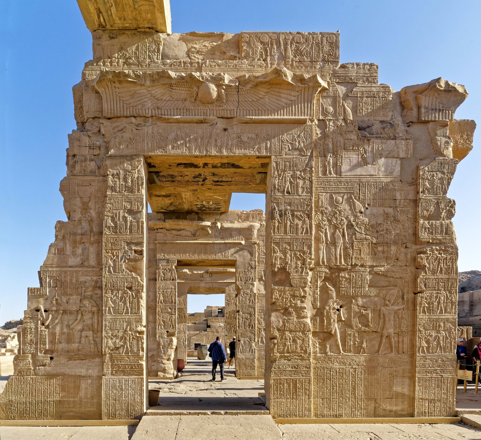 Una serie di portali di pietra allineati nel tempio di Kom Ombo, con il cielo azzurro oltre l'ultimo
