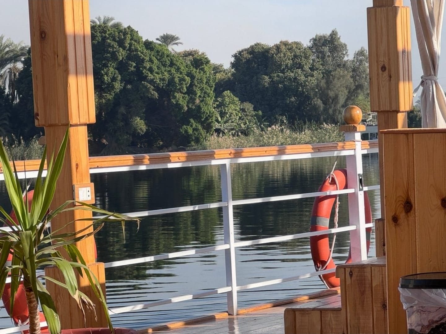 Il ponte della dahabiya Akhenaton davanti a una riva verde