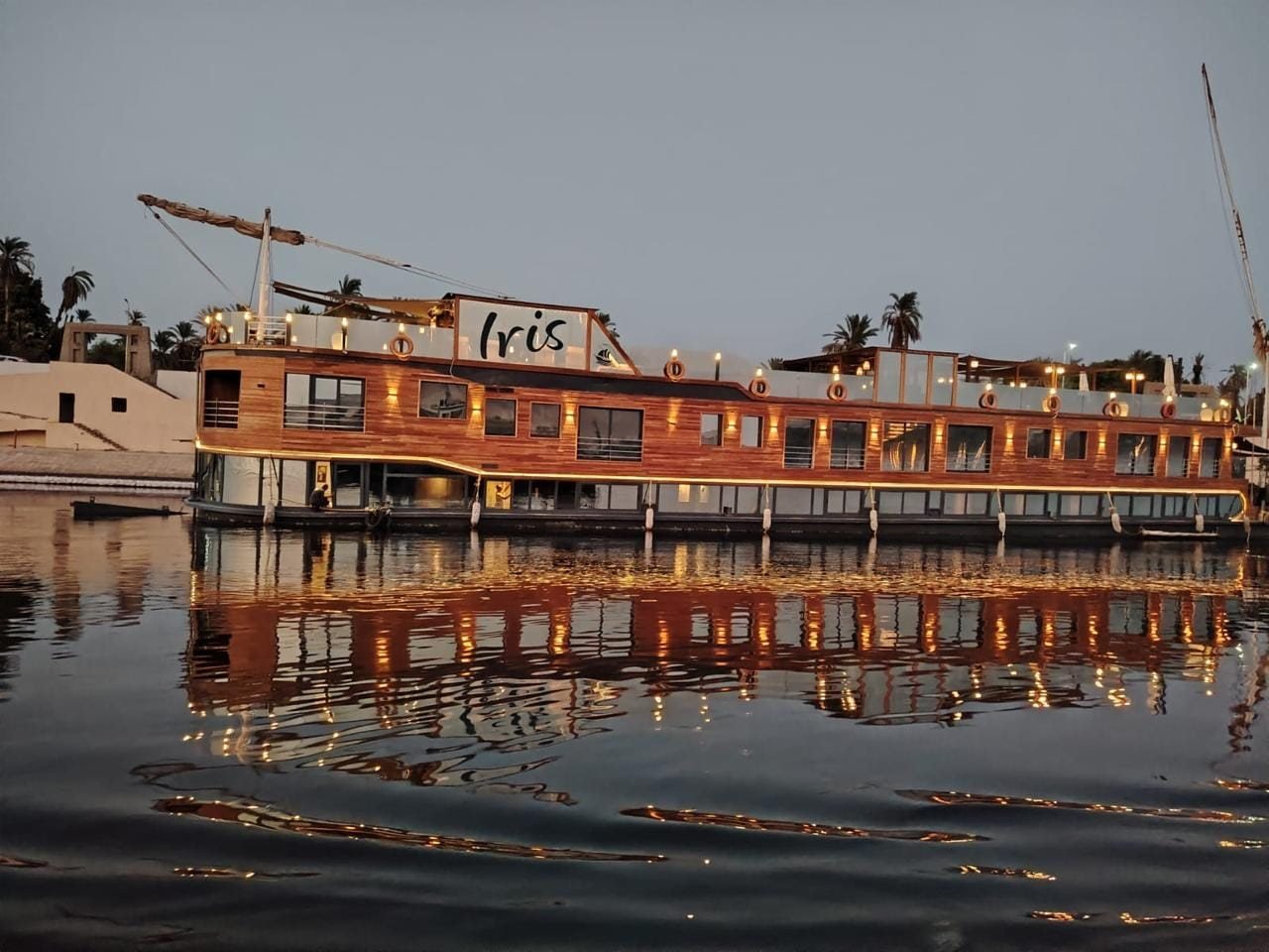La dahabiya Iris illuminata all’ormeggio, riflessa nel Nilo al calar della notte
