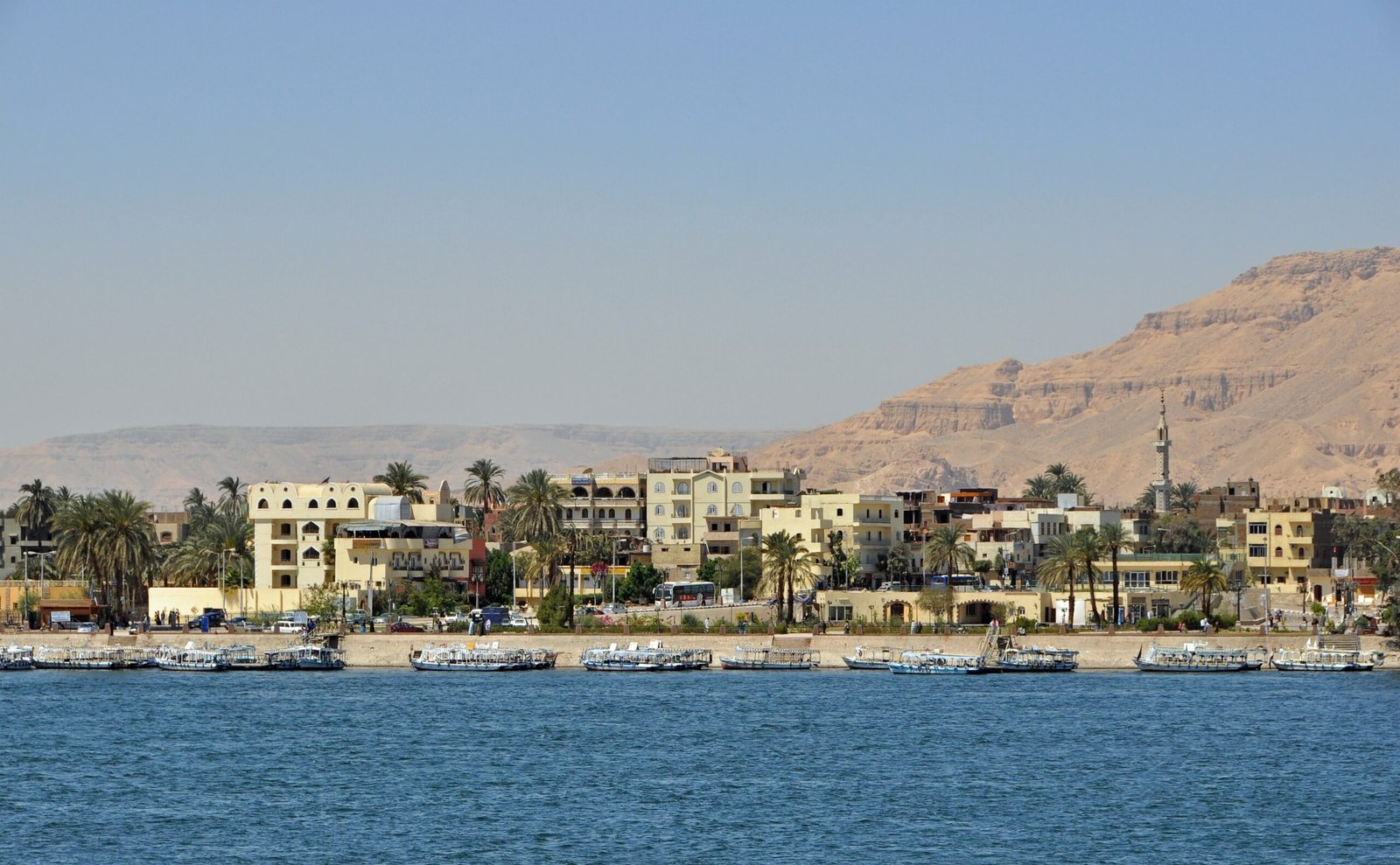 Il lungofiume di Luxor sulla riva est, con le case, un minareto e le colline della riva ovest dietro