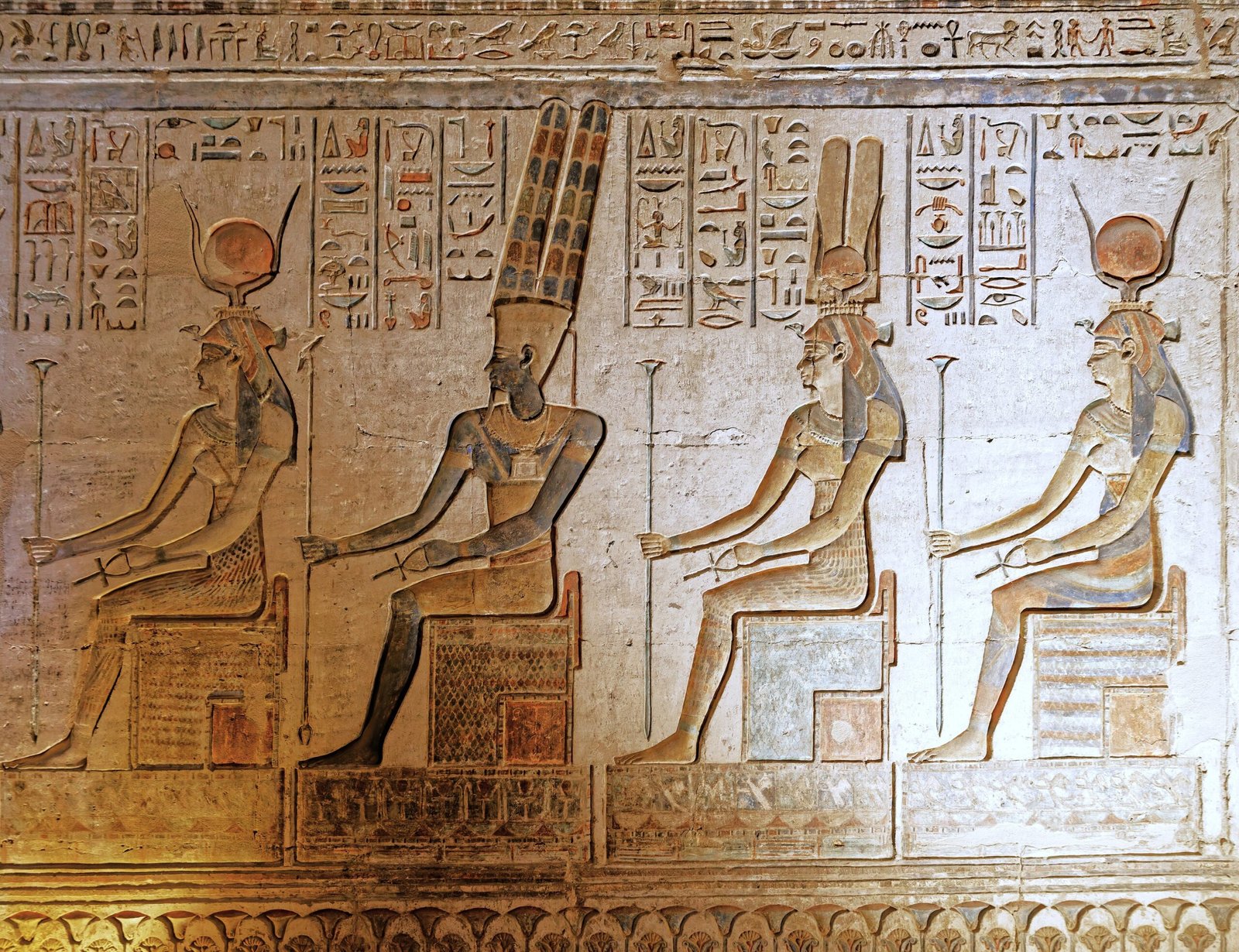 Quattro divinità sedute in un rilievo colorato del tempio di Hathor a Deir el-Medina