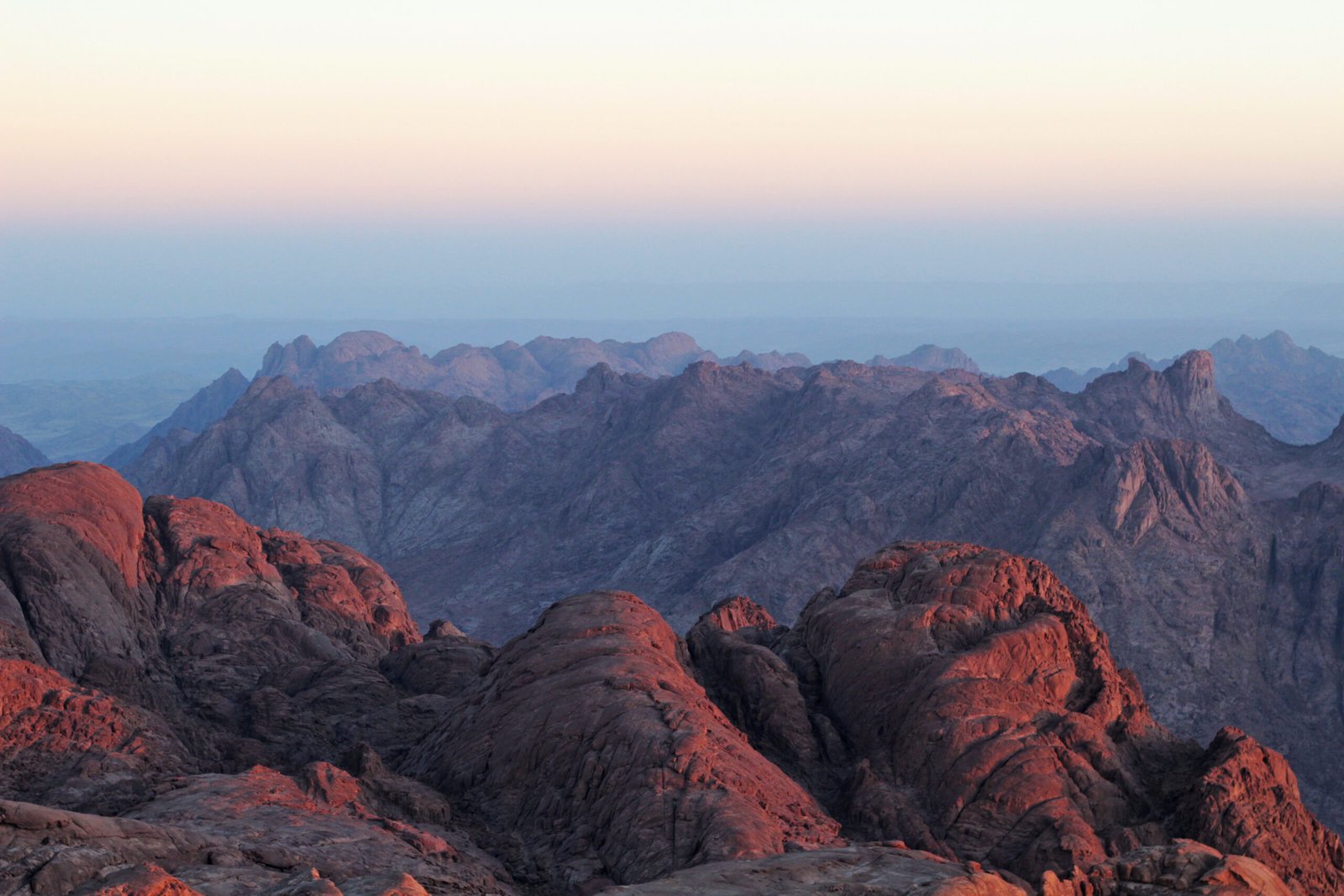 Le cime di granito rosso del Sinai illuminate dalla luce dell'alba, con le valli azzurre in fondo
