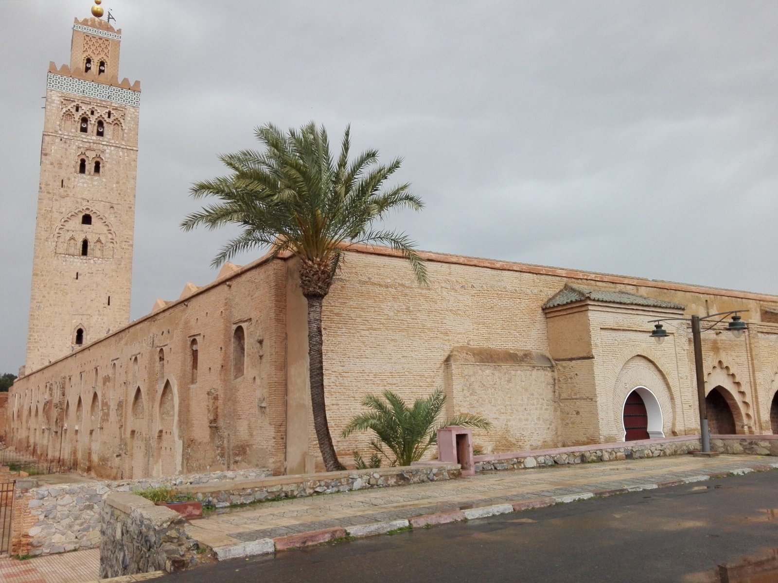 Il minareto della moschea Koutoubia a Marrakech con una palma accanto alle mura dell'edificio