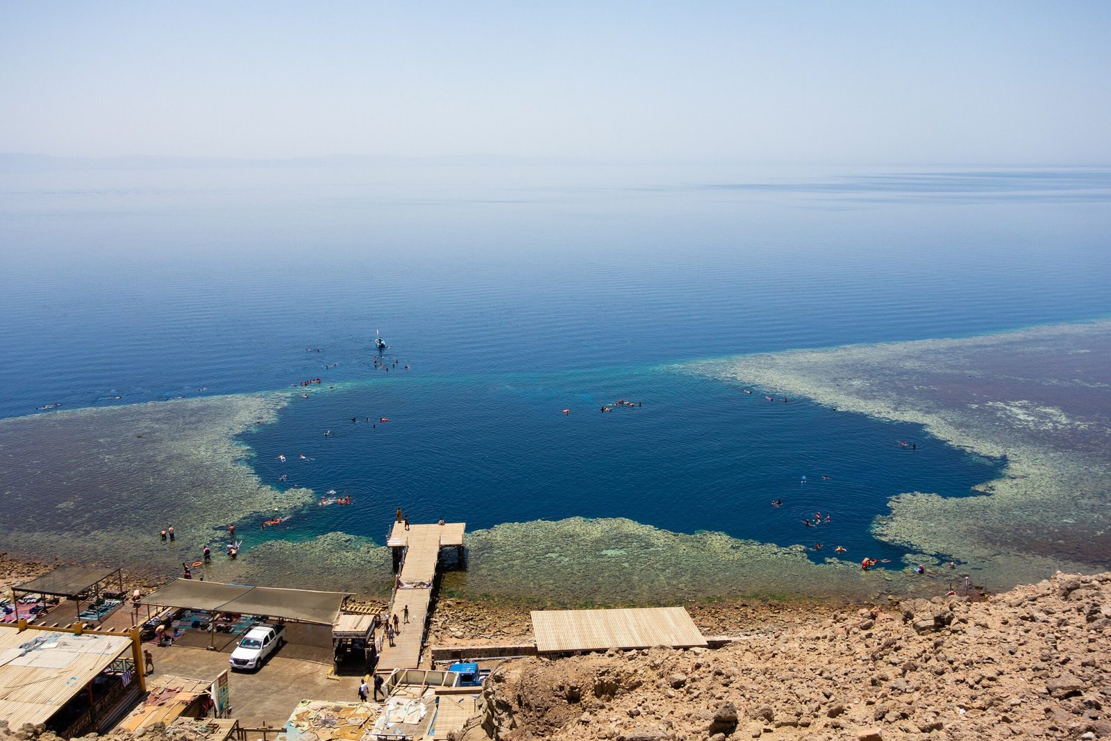 Il Blue Hole di Dahab visto dall'alto, con il cerchio blu scuro nella barriera corallina e il pontile sulla riva