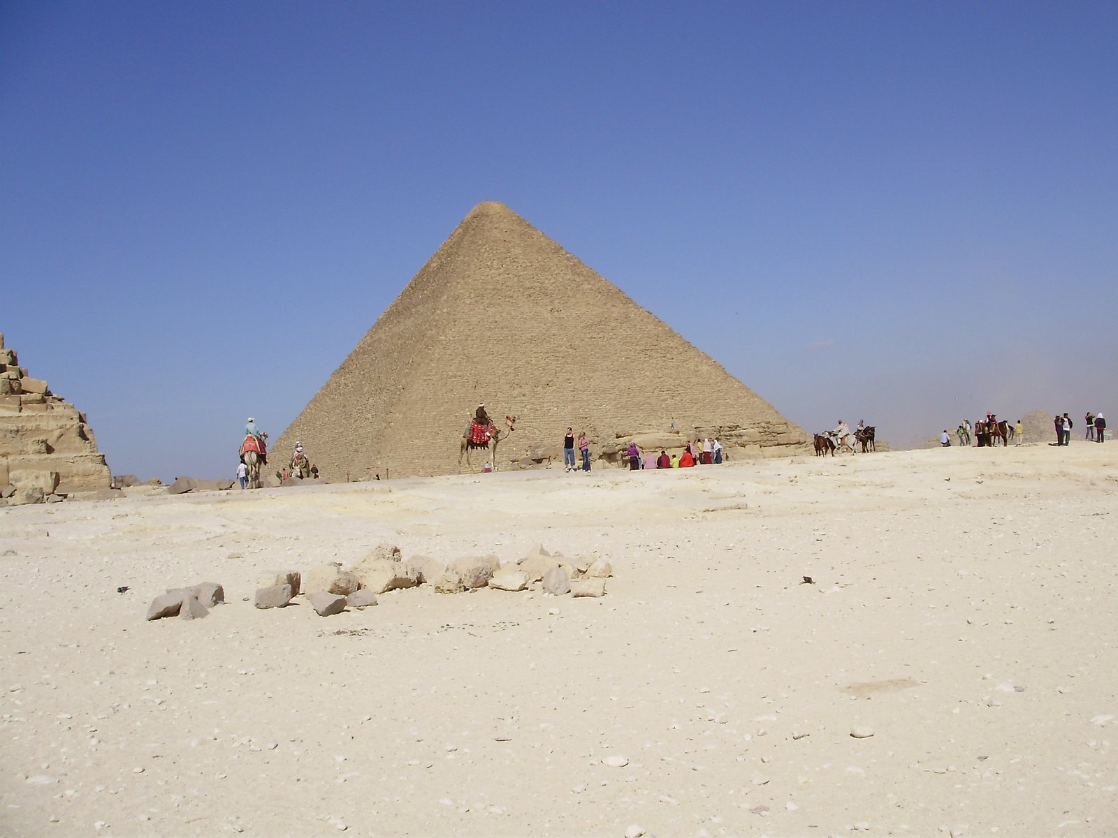 La grande piramide di Giza sulla sabbia chiara, con i visitatori ai piedi