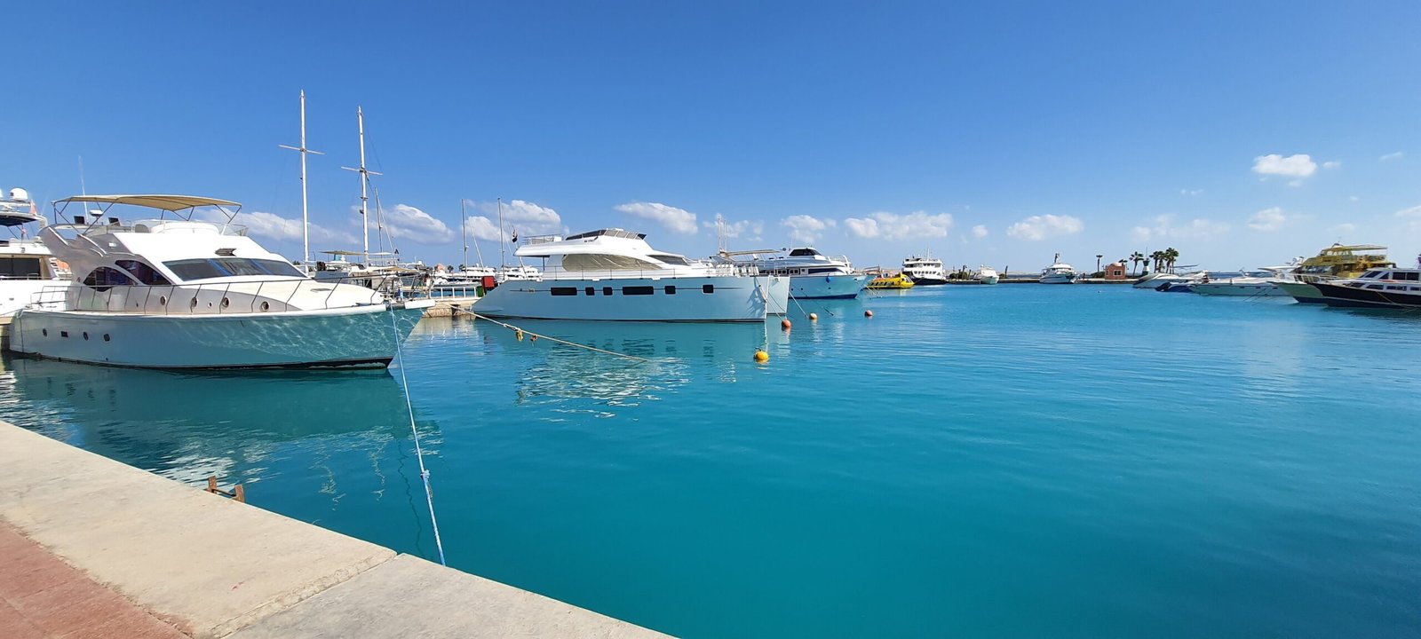 Gli yacht ormeggiati nell'acqua turchese della marina di Hurghada, sotto un cielo azzurro con nuvole sparse