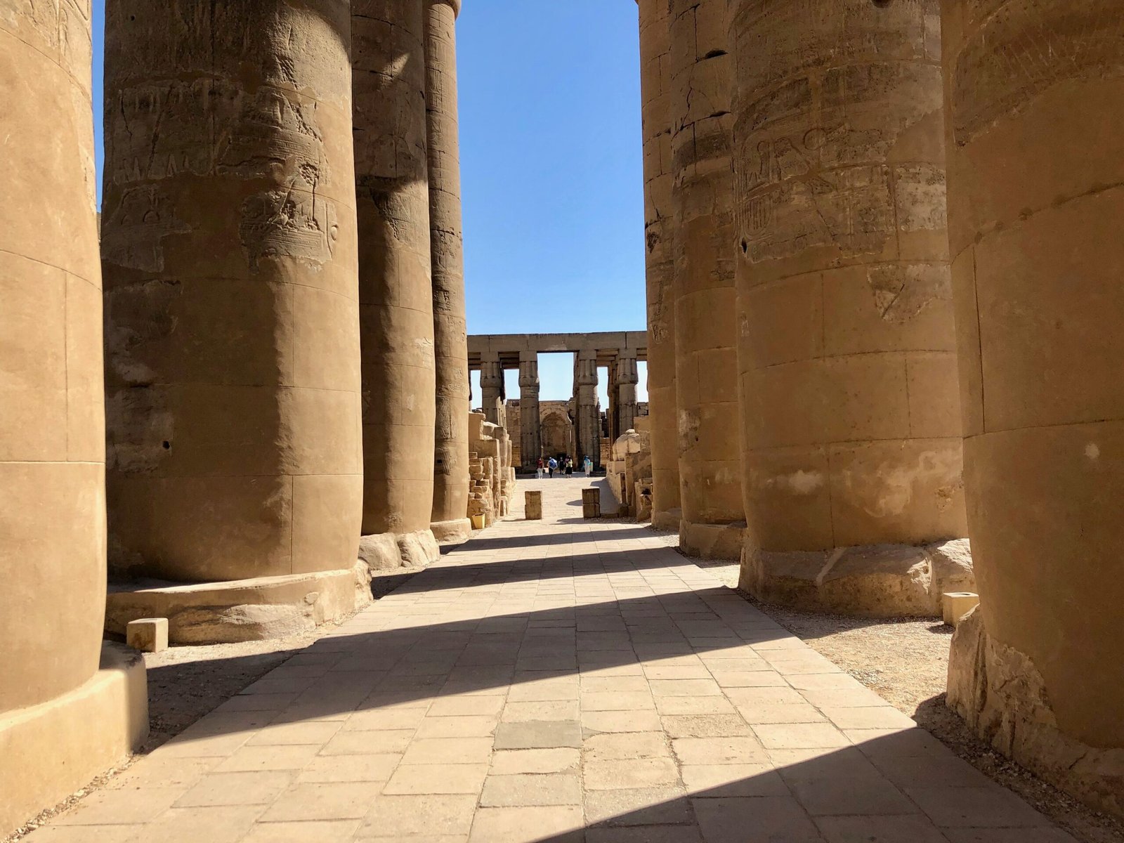 Un passaggio tra le grandi colonne del tempio di Luxor, con le ombre nette sul pavimento di pietra
