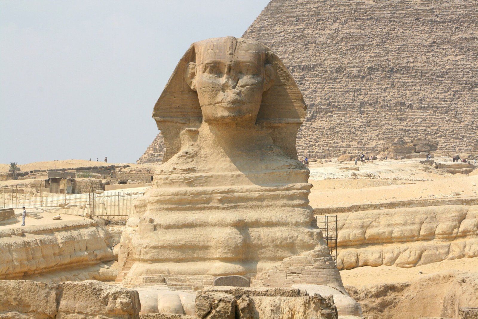 La Sfinge di Giza vista di fronte, con il corpo di roccia stratificata e la piramide dietro