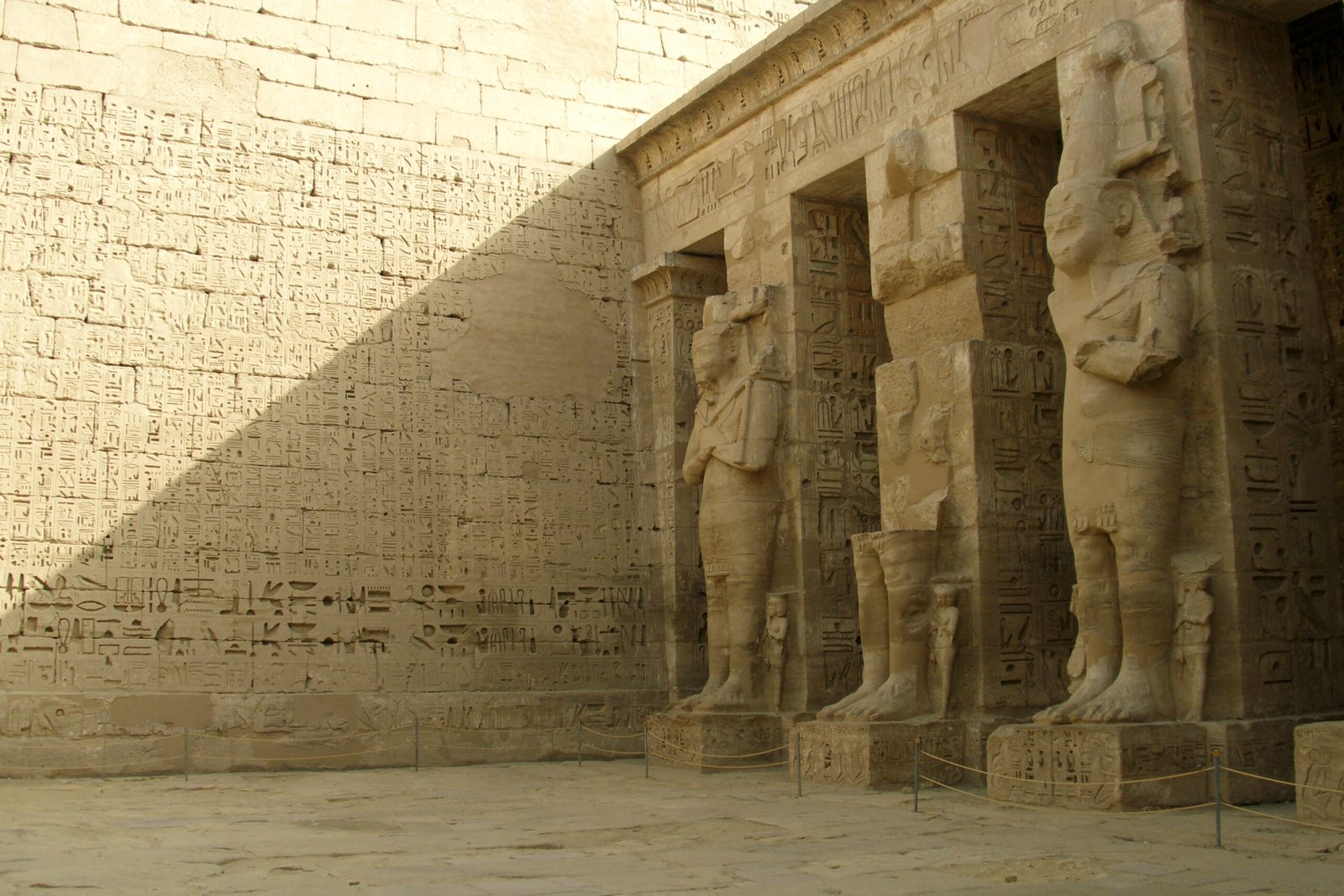 Il cortile di Medinet Habu con le statue osiriache di Ramses III e il muro coperto di scritture