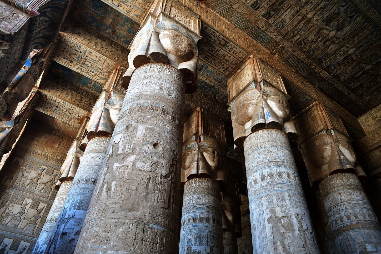 Le colonne di Hathor nel tempio di Dendera viste dal basso, con i capitelli e il soffitto decorato