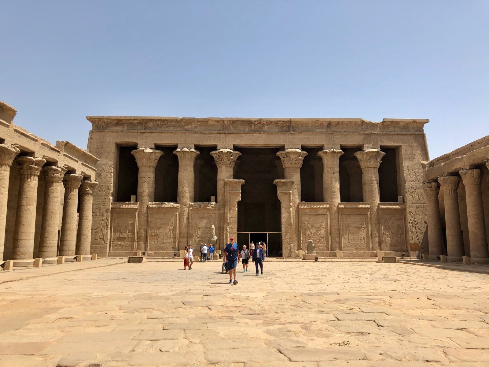 La facciata a colonne del cortile del tempio di Edfu, con pochi visitatori in lontananza