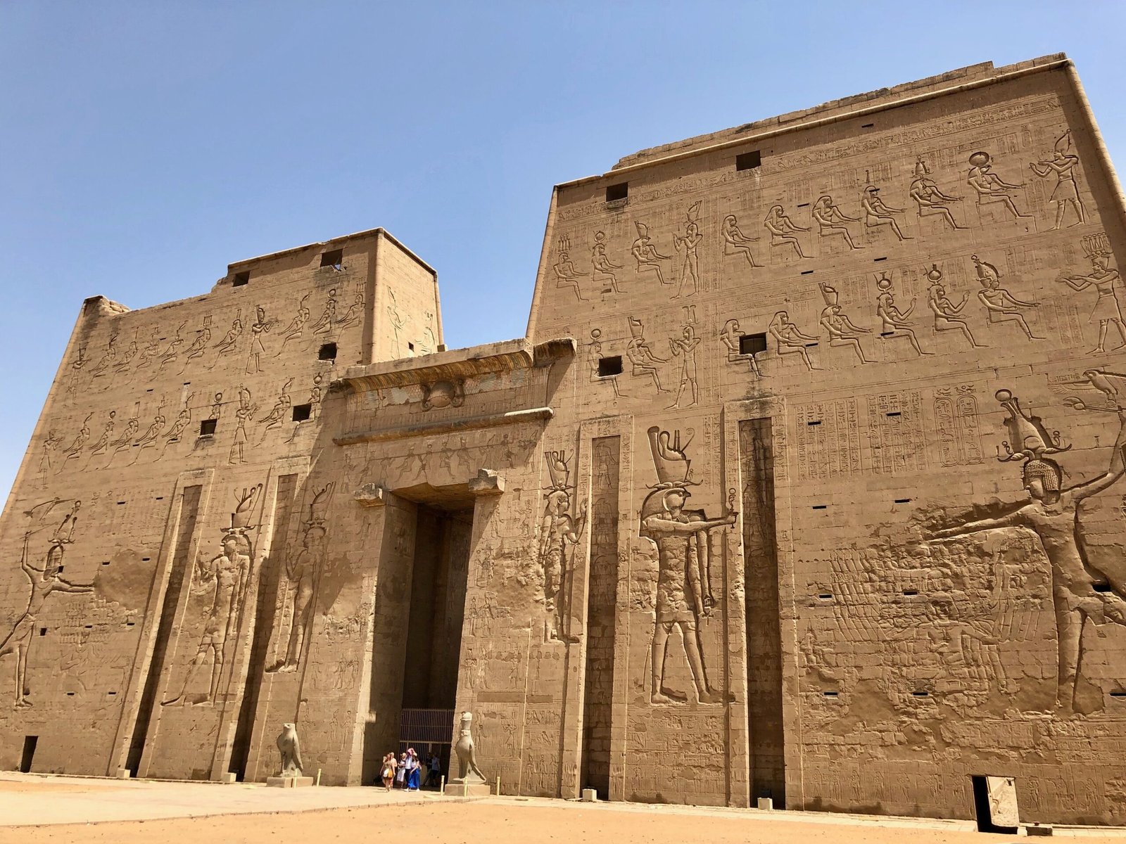 Il grande pilone del tempio di Edfu con i rilievi di Horus e del faraone, sotto un cielo azzurro