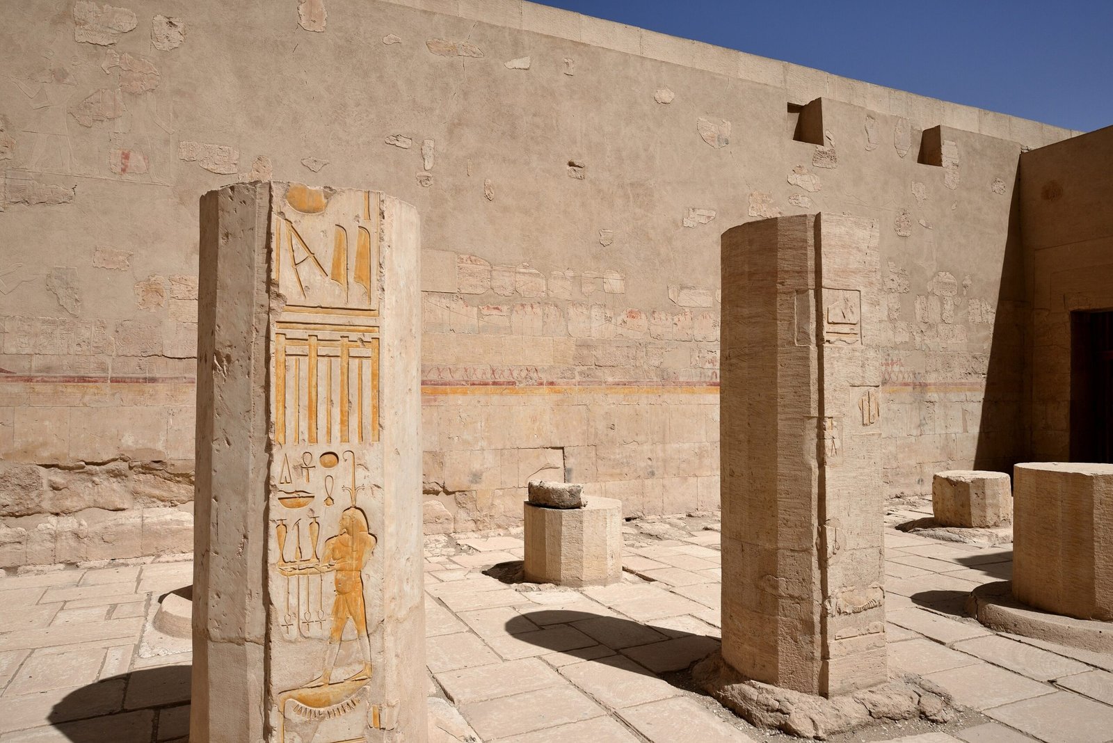 Un cortile del tempio di Hatshepsut con due pilastri incisi di geroglifici e ombre nette sul pavimento