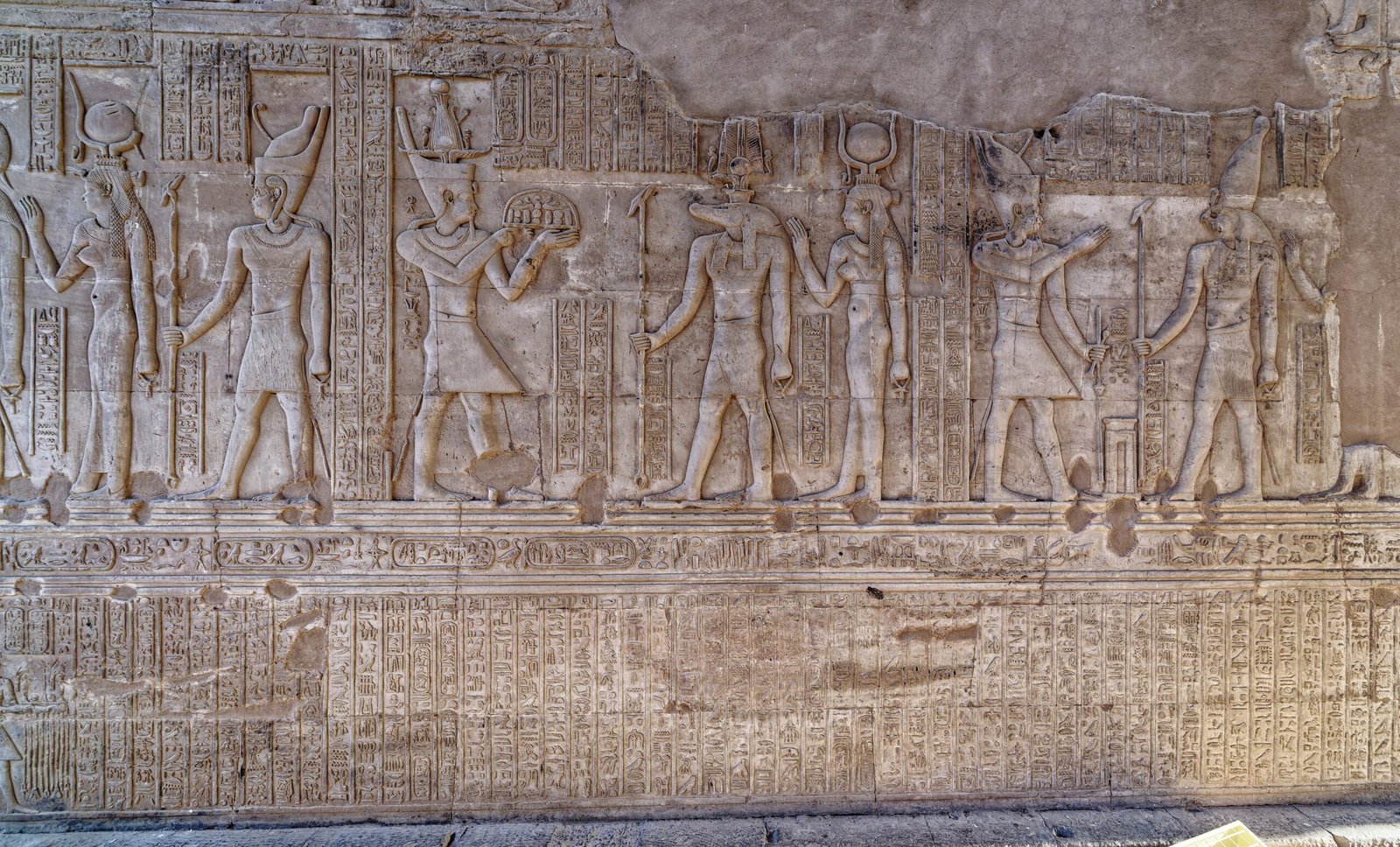 Una lunga fascia di rilievi con divinità e geroglifici su una parete del tempio di Kom Ombo