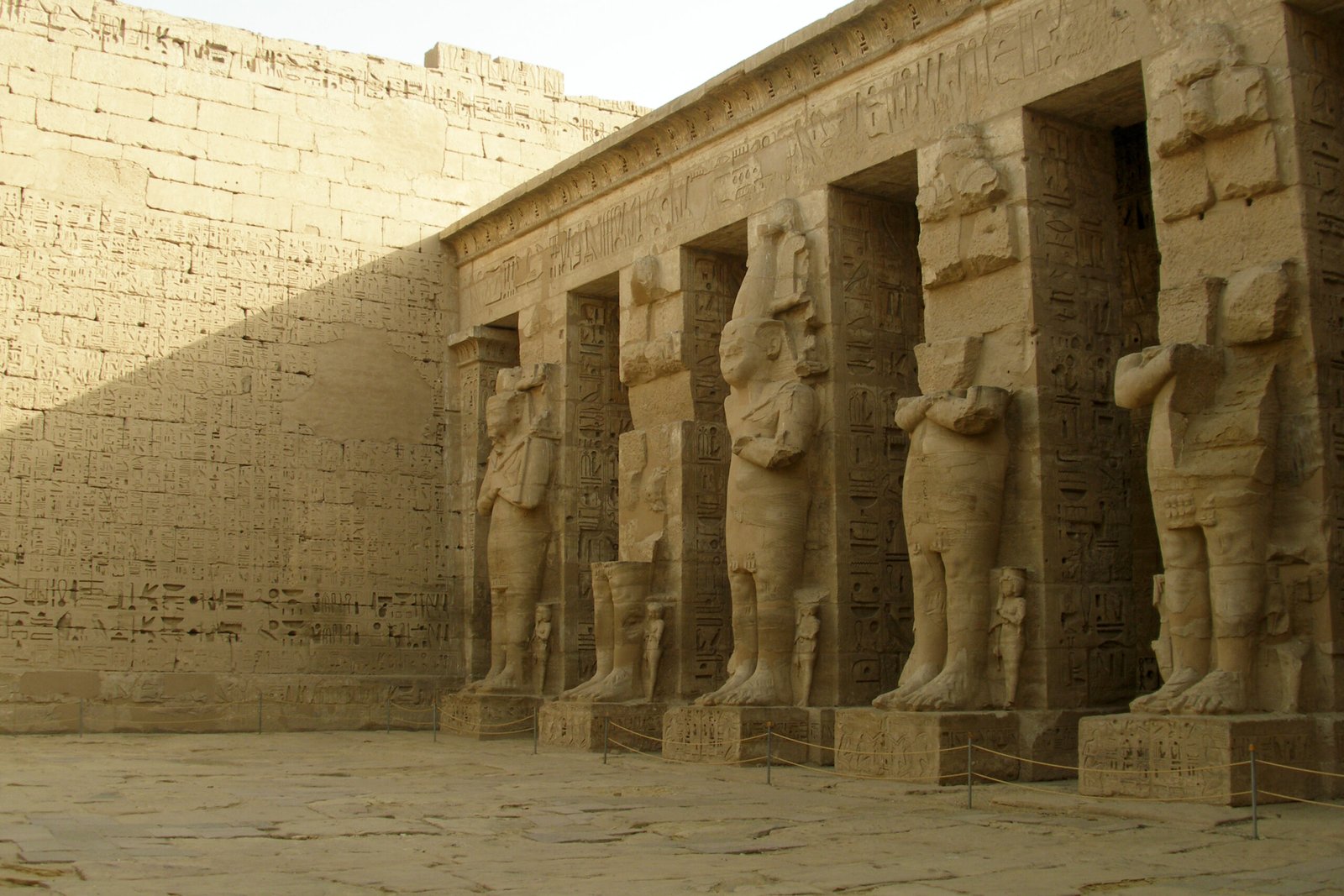Le statue osiriache addossate ai pilastri del cortile di Medinet Habu, nella luce del pomeriggio