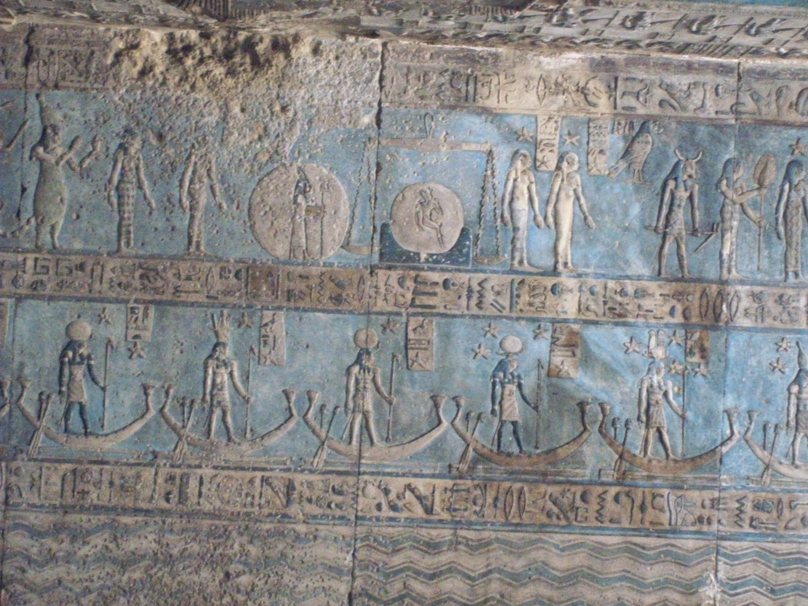 Le barche solari e le figure di divinità dipinte di azzurro su una parete del tempio di Dendera