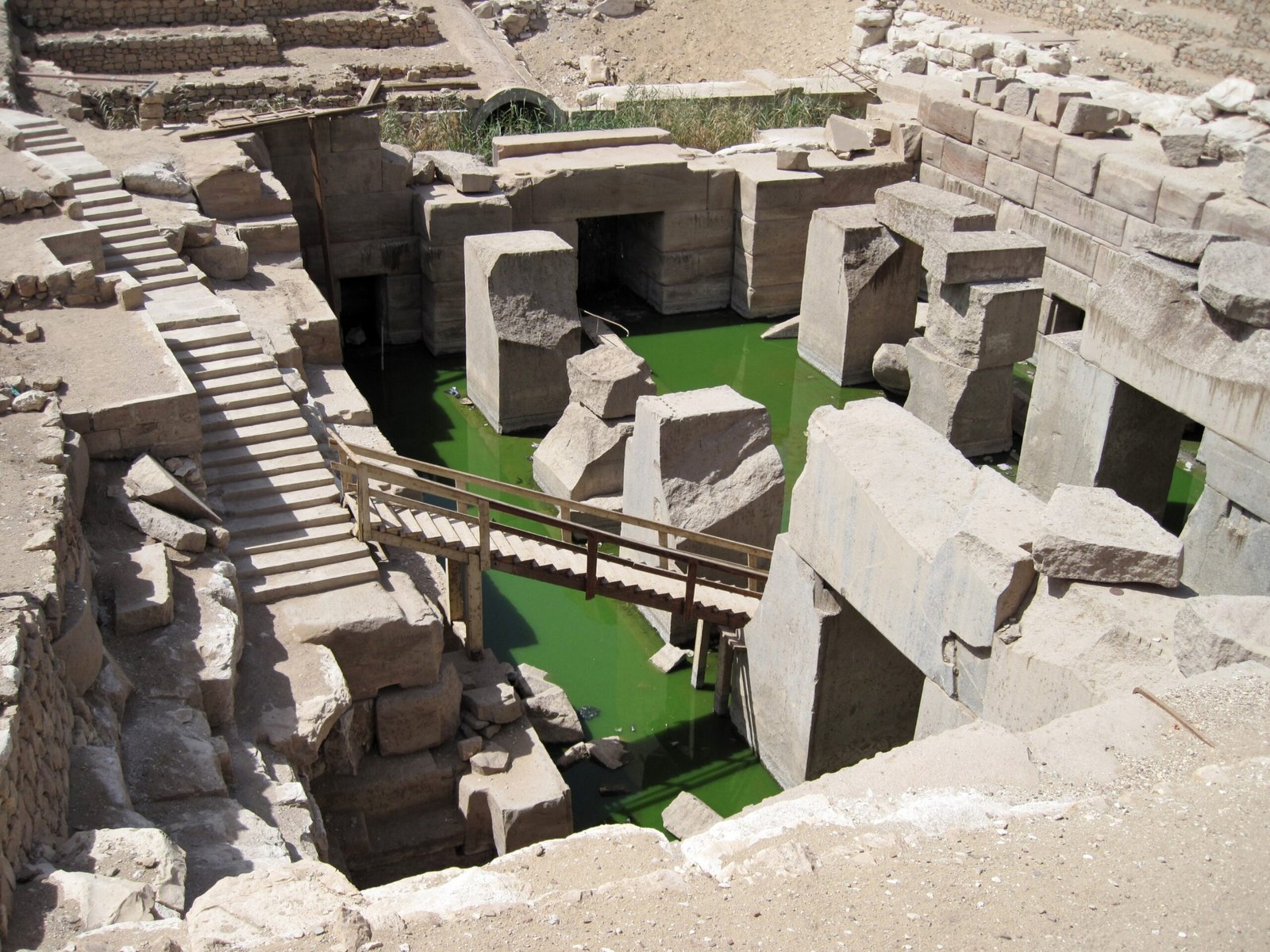 L'Osireion di Abydos visto dall'alto, con la scala di legno e l'acqua verde tra i grandi blocchi di pietra